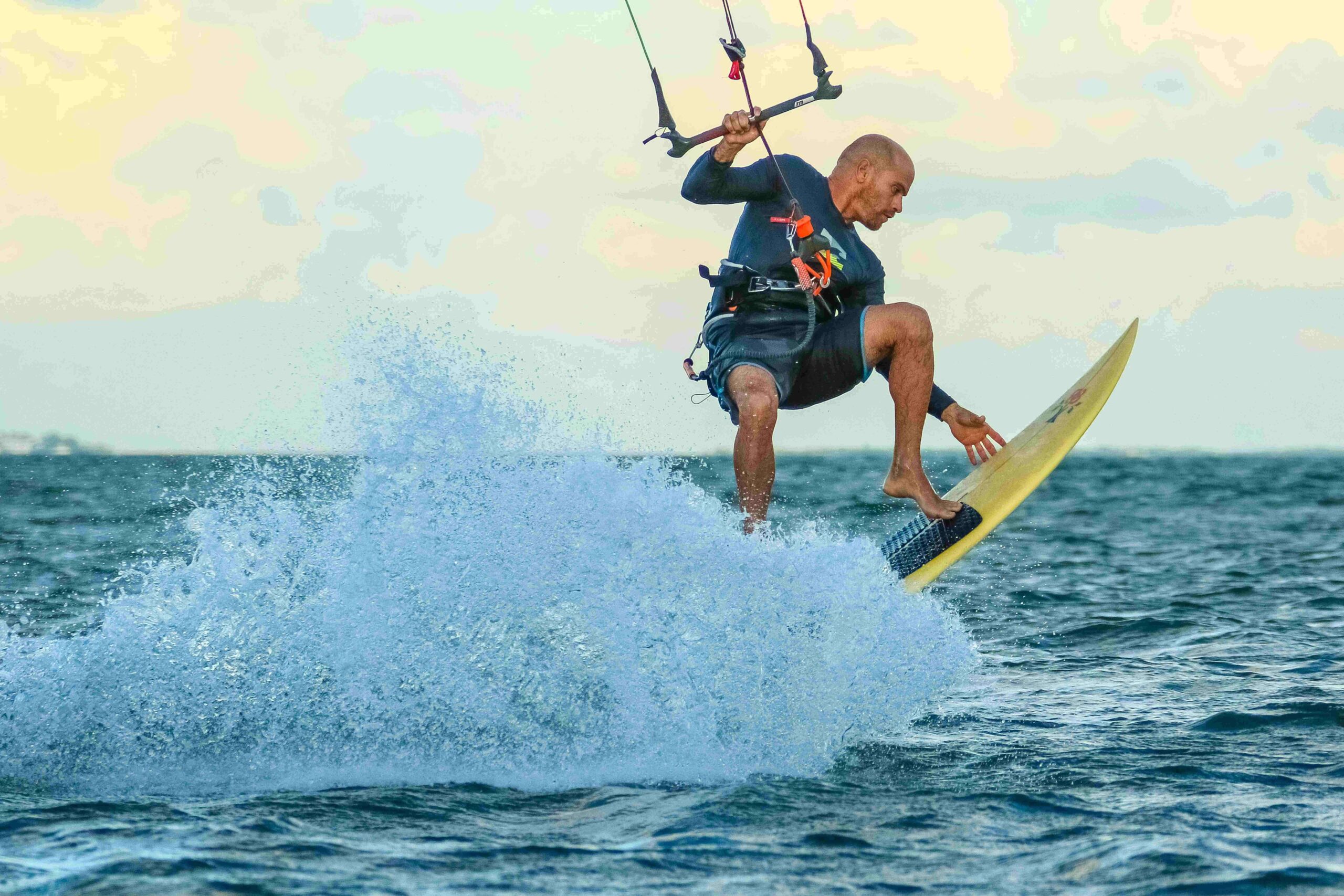 Man kiteboarding on the ocean with waves and splashes, capturing action and excitement.