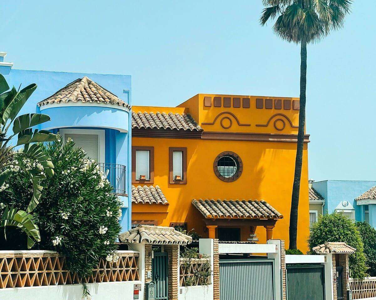 yellow and white concrete building near green tree under blue sky during daytime