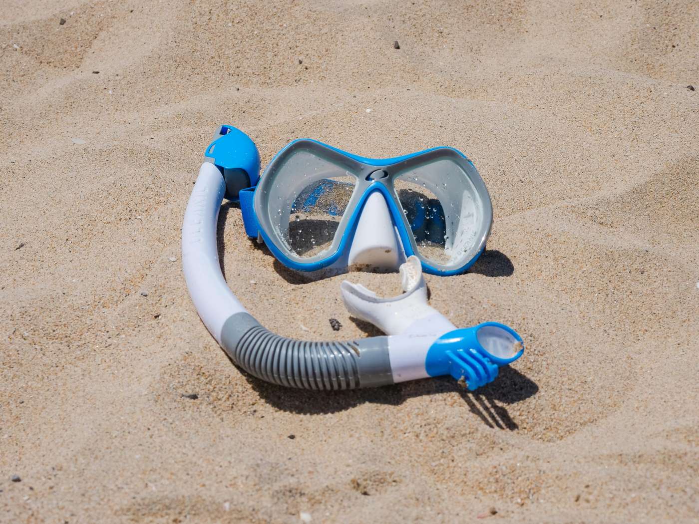 8093156 Blue snorkel mask set on a sandy beach, ideal for travel and summer themes.