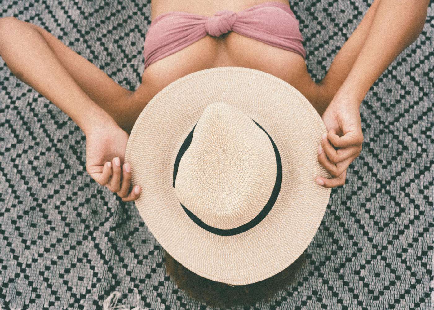 3621637 Woman sunbathing with straw hat and bikini top, embracing summer vibes.
