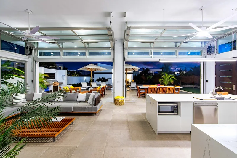 Open-plan villa living space opening onto the pool terrace at dusk