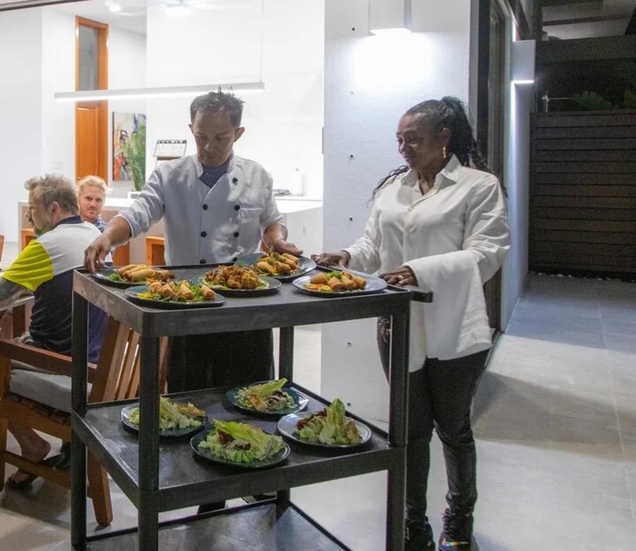 A White Villas private chef serving plated dishes to guests inside the villa